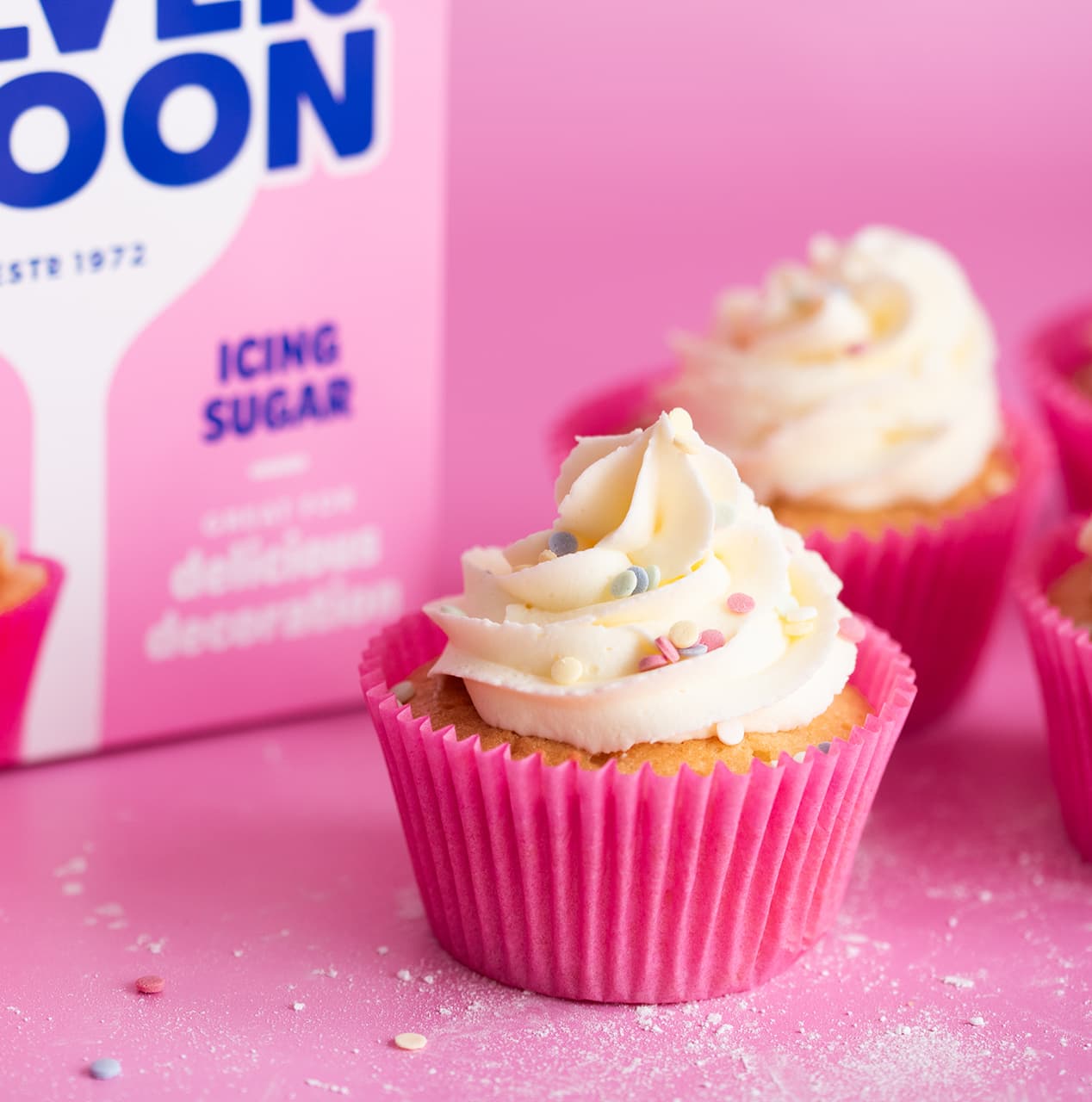 Pretty fairy cakes decorated with white icing and colourful sprinkles.